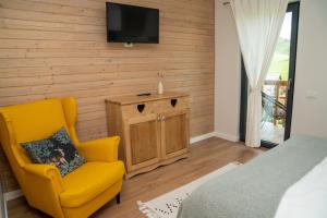 a bedroom with a yellow chair and a tv on a wall at Casa de Sub Munte Fundata in Fundata