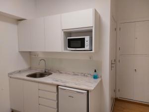 a kitchen with white cabinets and a sink and a microwave at Estúdio na Carreira in Elvas