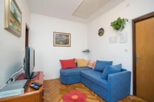 ein Wohnzimmer mit einem blauen Sofa und einem TV in der Unterkunft Apartments Nataša in Supetar