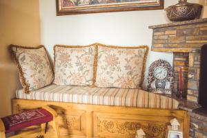 a couch with two pillows and a clock on a fireplace at Violetta's House Παραδοσιακή Βίλα στην Πορταριά in Portariá