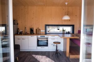 a kitchen with white cabinets and a wooden table at Tiny-House mit großer Terrasse zum Genießen! 