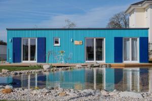 a blue house with a pond in front of it at Tiny-House mit großer Terrasse zum Genießen! 