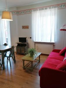 a living room with a red couch and a table at Appartamenti Val di Fassa Passo Costalunga 223, 119, 114 in Vigo di Fassa