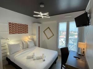 a bedroom with a bed and a desk and a television at Les Cols Verts - Logis Hôtels in La Tranche-sur-Mer