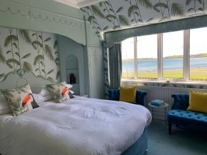 a bedroom with a bed and two blue chairs at Cairn Bay Lodge in Bangor