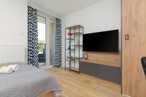 a bedroom with a bed and a flat screen tv at Warsaw Praga Kokoryczki Apartments with Parking by Renters in Warsaw