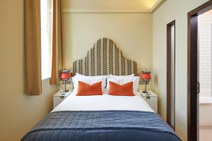 a bedroom with a large bed with orange pillows at Hotel du Vin Exeter in Exeter