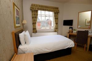 una camera d'albergo con letto, scrivania e finestra di Vine, Stafford by The White Feather Group Ltd a Stafford