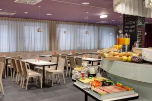 فندق ماينينغر فيينا داونتاون سيسي في فيينا: مطعم يوجد به طاولات وكراسي مع طعام