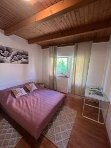 - une chambre avec un lit violet et une fenêtre dans l'établissement Apartman Delnice Park Srna, à Delnice