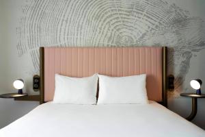un letto con 2 cuscini bianchi e una testiera del letto di ibis Styles Paris Porte de Versailles - Mairie d'Issy a Issy-les-Moulineaux