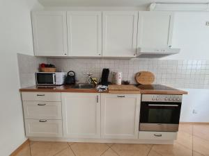 eine Küche mit weißen Schränken, einer Spüle und einer Mikrowelle in der Unterkunft Biggesee-Sauerland in Drolshagen