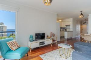 ein Wohnzimmer mit einem blauen Sofa und einem TV in der Unterkunft Forum Apartment in Funchal