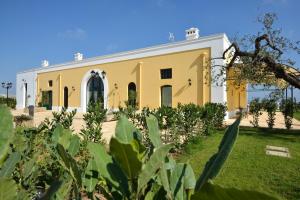 a yellow building with a garden in front of it at Tenuta Orsanese in Ginosa Marina