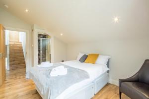 a bedroom with a white bed and a chair at Tulse Hill Luxury Cosy Rooms in London