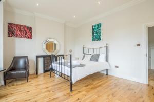 a bedroom with a bed and a chair and a mirror at Tulse Hill Luxury Cosy Rooms in London