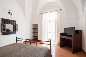 a bedroom with a bed and a desk and a window at Tenuta Dammuso Soledad in Scauri