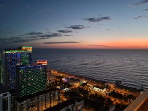 a view of the ocean and buildings at night at ORBY CITY HOTEL 5* in Batumi