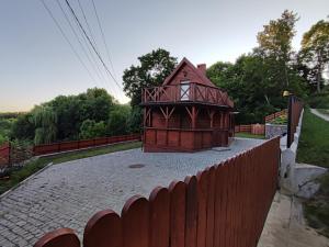 una pequeña casa está sentada junto a una valla en Bug Na Skarpie - Domek Wypoczynkowy z Jacuzzi i Kominkiem en Drohiczyn nad Bugiem