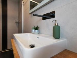 a bathroom sink with a green soap dispenser on it at Neues City Center Piano Appartement mit Netflix in Klagenfurt
