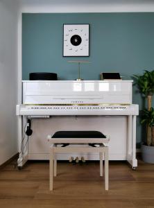 a white piano in a room with a blue wall at Neues City Center Piano Appartement mit Netflix in Klagenfurt