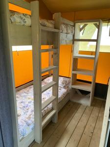 2 Etagenbetten in einem Zimmer mit orangefarbener Wand in der Unterkunft BG Apartments Safaritent in Somogyhatvan