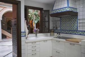 una cocina con armarios blancos y azulejos azules y blancos en La casa del Cipres una casa con historia, en Córdoba