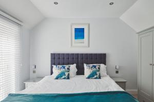 a white bedroom with a large bed with blue pillows at Chance Cottage in St Ives