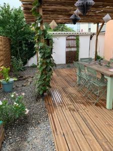 a wooden deck in a backyard with a table and a vine at Le Clos de l'Olivier in Alès