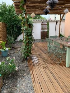 drewniany taras na podwórku ze stołem i winoroślą w obiekcie Le Clos de l'Olivier w mieście Alès