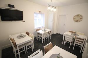 a dining room with tables and chairs and a flat screen tv at Media Manor - Fully Refurbished in 2022 - Large 6 Bedrooms, 3 Bathrooms plus Media Games Room in Blackpool