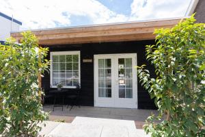 a black house with a white door and a table at B&B The Wellness Cottage in Dordrecht