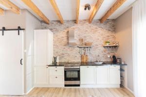 a kitchen with white cabinets and a brick wall at B&B The Wellness Cottage in Dordrecht