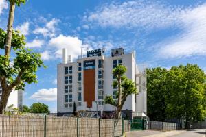 Un bâtiment blanc avec un panneau en haut dans l'établissement Kyriad Paris Ouest - Colombes, à Colombes