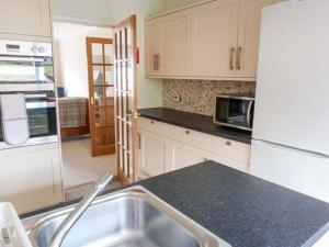 a kitchen with white cabinets and a black counter top at Hillfoot in Kingussie