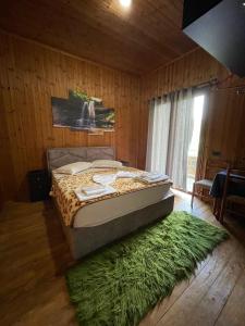 a bedroom with a bed and a green rug at KT Qato Hotel in Bogovë