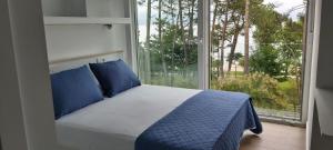 a bed with blue pillows in a room with a window at HOSTAL FORMOSO in San Francisco