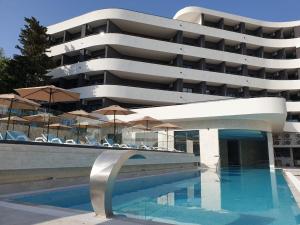 a hotel with a swimming pool with chairs and umbrellas at Montenegrina Hotel & SPA All-Inclusive in Becici