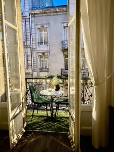 Une porte ouverte s'ouvre sur un balcon avec une table et des chaises. dans l'établissement Cœur de ville, appartement de caractère, à Nancy