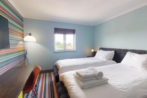 a hotel room with two beds and a table and a window at Village Hotel Bournemouth in Bournemouth