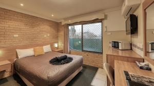 a bedroom with a bed and a large window at Forest Lodge Motor Inn & Restaurant in Dubbo