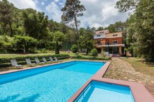 un domaine avec une piscine et une maison dans l'établissement L'aviador de Can Ton, in the middle of nature with its own stream, à Sant Llorenc Savall