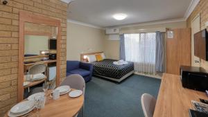 a hotel room with a bed and a dining room at Forest Lodge Motor Inn & Restaurant in Dubbo