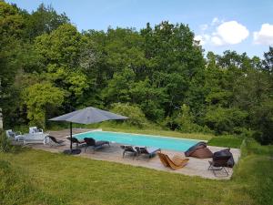 a swimming pool with chairs and an umbrella at Gîte de Chantegrel in Fleurac