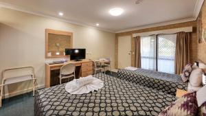 a hotel room with two beds and a desk at Forest Lodge Motor Inn & Restaurant in Dubbo