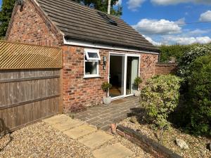 a brick house with a gate and a garage at Wagtail Cottage in Tarporley