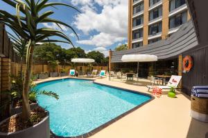a swimming pool with a palm tree next to a building at Atura Albury in Albury