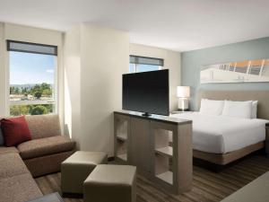 a hotel room with a bed and a flat screen tv at Hyatt House LA - University Medical Center in Los Angeles