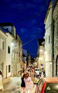 Un gruppo di persone che camminano per strada di notte di APARTMANI CENTAR VODICE a Vodice