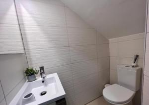 a white bathroom with a toilet and a sink at Casa do Gaspar in Aveiro